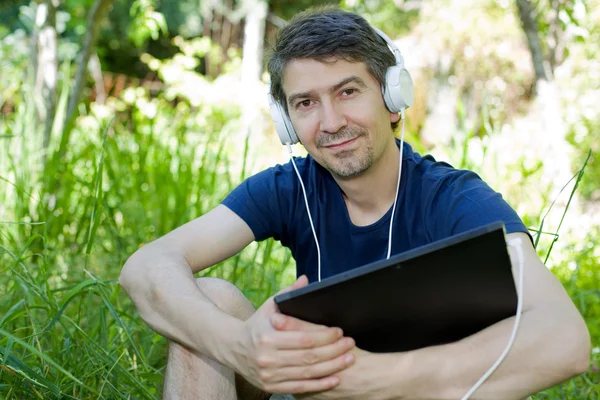 Casual man holding a tablet with headphones, outdoor — Stock Photo, Image