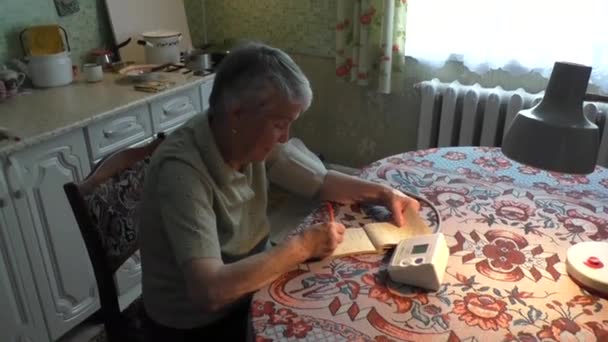 Frau nimmt arteriellen Blutdruck und notiert in Notizbuch — Stockvideo