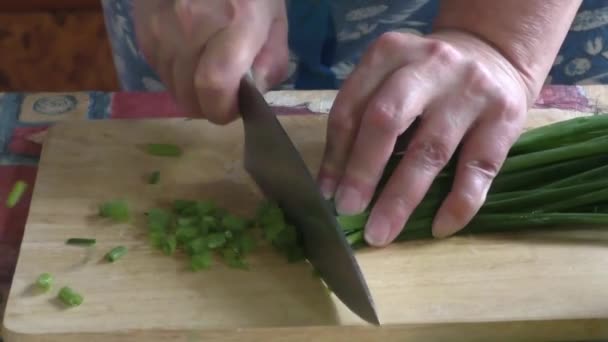 Женщина режет зеленый лук — стоковое видео