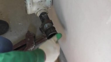 Bir adam bir somun boru demir radyatör üzerinde tutar.