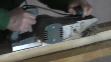 Bir adam çalışma hardal elektrik ahşap bir bloğu.