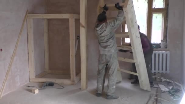 Двое рабочих устанавливают деревянные лестницы — стоковое видео