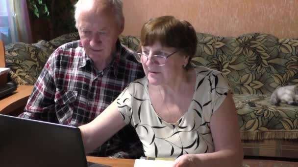 Starsze pary przy stole z notebookiem — Wideo stockowe