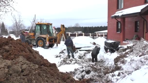 PERM, RUSSIA, DECEMBER 15.2015: Трудящиеся-мигранты и экскаватор работают на строительной площадке — стоковое видео
