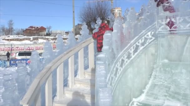 Dauerwelle, Russland, 6. Februar 2016: Fröhliche Kinder fahren auf einer Spielrutsche in der Eisstadt — Stockvideo