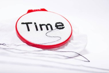 Zaman kavramını bir iğne, iplik ve siyah boncuklarla bembeyaz arkaplanda işlenmiş 