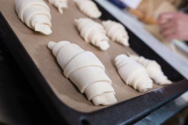 Çiğ kruvasanlar odak noktasında kapanıyor ve elleri arka planda merdane gibi..