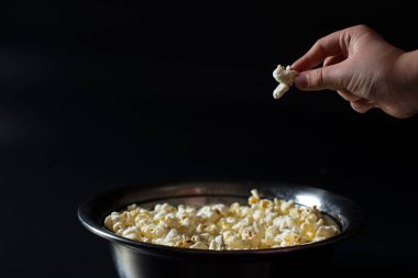 Çocuk el siyah arka planda bir kovadan patlamış mısır aldı.