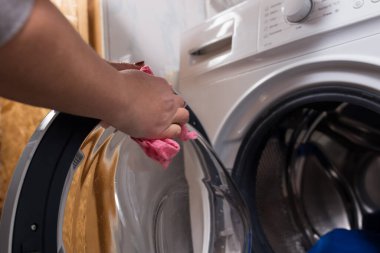 Yıkandıktan sonra çamaşır makinesini temizleyen bir kadının elleri..