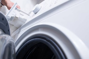 Çamaşır makinesine çamaşır tozu koymak. Evde çamaşır günü.