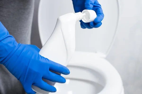 背景に便器付きのトイレ掃除機を使用した青い手袋の手 — ストック写真