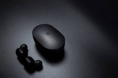 Xiaomi Havayolları 'ndan siyah süpürge kulaklıkları ve siyah arka planda şarj davası..