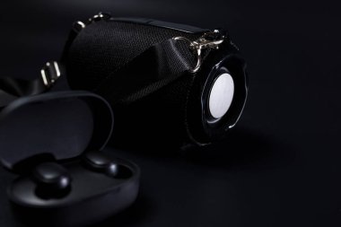 Siyah arkaplanda siyah kablosuz kulaklık ve bluetooth hoparlör..