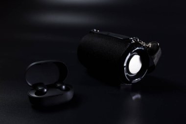 Siyah kablosuz kulaklık ve siyah arkaplanda kablosuz hoparlör..