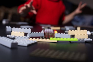 Lego 'yla çocuk yapmak. Çocuk eli inşaatçıdan tuğlaya ulaşıyor.