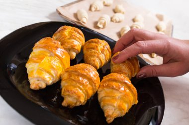 Arka planda çiğ kruvasan ve siyah tabakta craspy kruvasanları pişiriyorum..