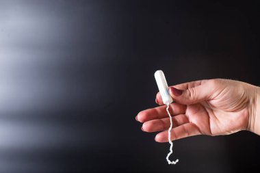 Kadın eli tamponu yakın tutuyor, siyah arkaplanda..