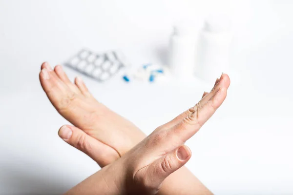 Female hands showing stop sign for  medicine pills on a white background.