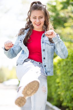 Duygusal ve güzel genç bir kadın şık giyinmiş, parkta yürüyor..