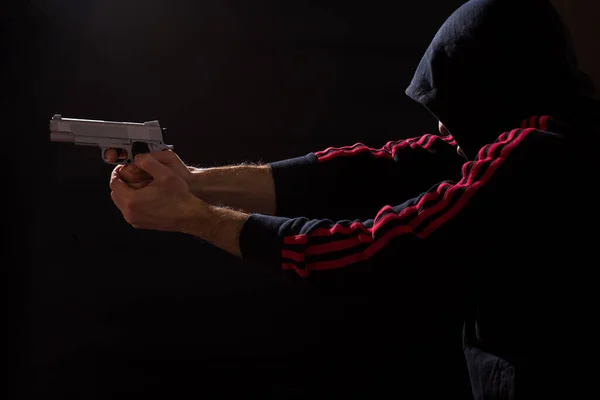 Man in sport wear pointing with gun on black background.