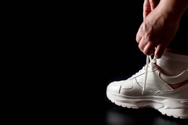 Siyaha izole edilmiş fotokopi çekilen spor ayakkabıları giyiyorum. Ayakkabı bağcıklarını beyaz spor ayakkabılara bağlıyorum..