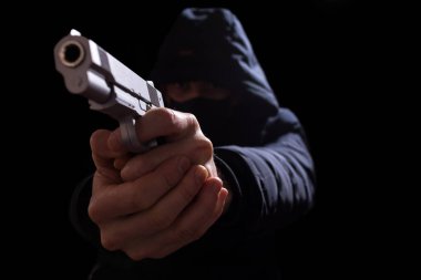 Silahlı ve kapüşonlu bir adam siyah bir sakızı yakın mesafeden hedef alıyor..