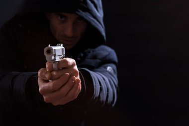 Wintaer ceketli, kapüşonlu silahlı, siyah arka planda fotokopi alanı olan bir adam..