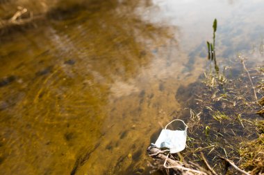 Küçük bir nehirde kullanılan tıbbi maske, fotokopi alanı olan güneşli bir gün..