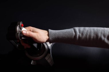 Siyah arka planda joystick ile uçak vurma oyunu oynayan bir erkek el..