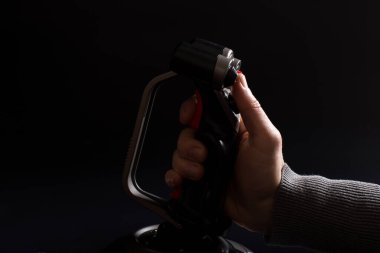 Erkek el ele tutuşan uçak kumandası. Parmağı tetikte, siyah arka planda..