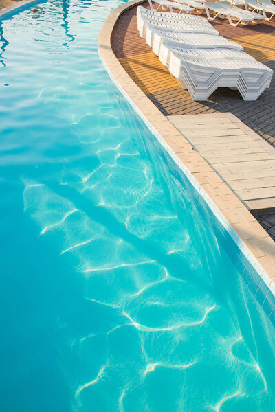 Luxury spa poolside with lounges in light of sunset, during summertime vacation.