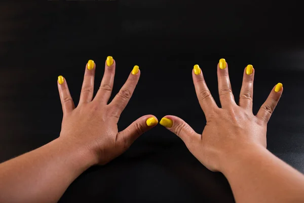 Kobiece Dłonie Żółtymi Paznokciami Zbliżyć Czarnym Tle — Zdjęcie stockowe