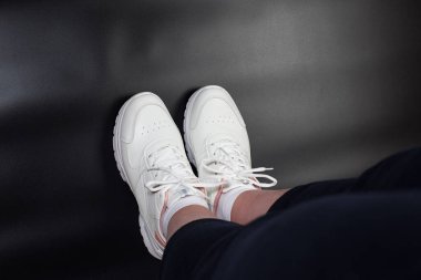 Female foots wearing up a sport shoes on black background with copy space.