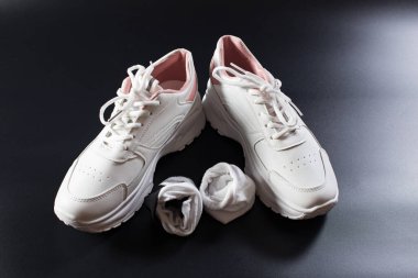 White sneakers with socks, close up on black background.