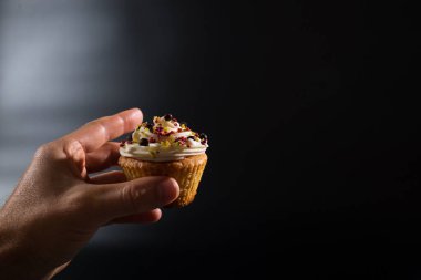 Siyah arkaplanlı ve fotokopi alanı olan güzel bir kek tutuyorum..