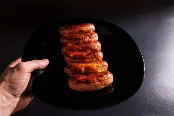 Waiter Hand Serving Roasted Sausages Plate Black Background — Stock Photo, Image