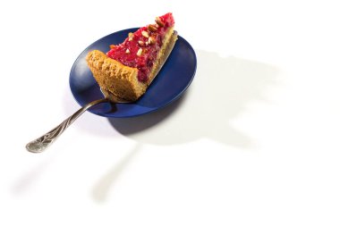 Bir parça meyveli kek tepside, gölgesi beyaz bir tabakta..