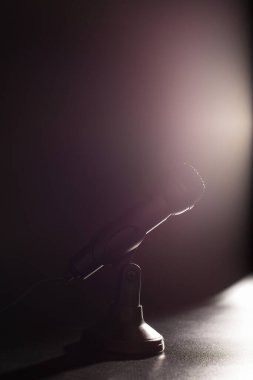 Siyah arkaplanda, sahne ışığı olan siyah bir mikrofon var..