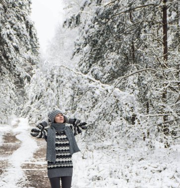 Genç kadın ormanda yürüyor ve karın tadını çıkarıyor.
