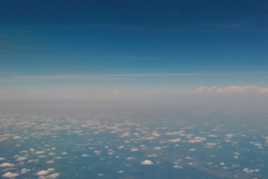 Mavi gökyüzünde, beyaz bulutların üzerinde uçuyor. Yeryüzünün yukarıdan görünüşü