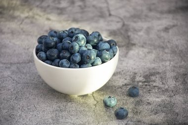 Beyaz fincanda gri beton arka planda taze yaban mersini hasadı.