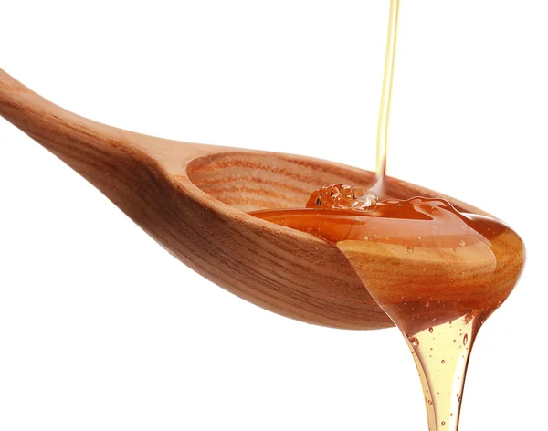 Honey dripping from wooden dipper — Stock Photo, Image