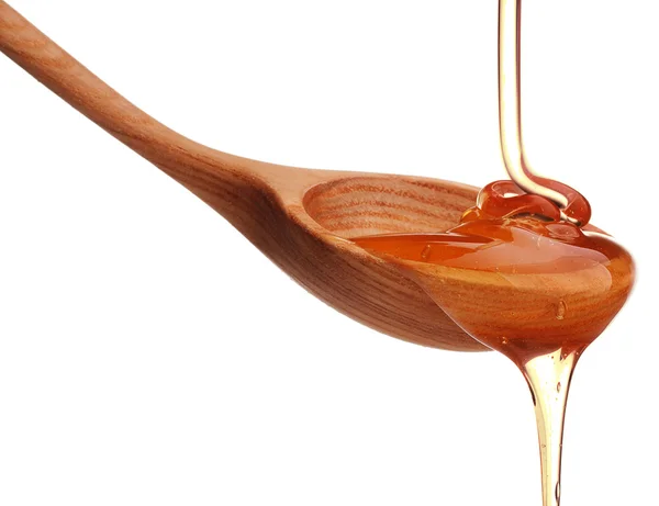 Honey dripping from wooden spoon — Stock Photo, Image