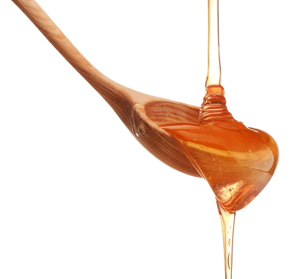 Honey dripping from wooden spoon — Stock Photo, Image