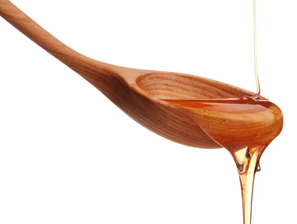 Honey dripping from wooden spoon — Stock Photo, Image