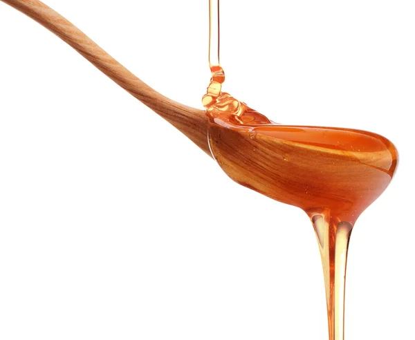 Honey dripping from wooden spoon — Stock Photo, Image