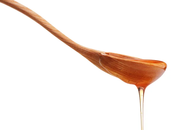 Honey dripping from a wooden dipper — Stock Photo, Image