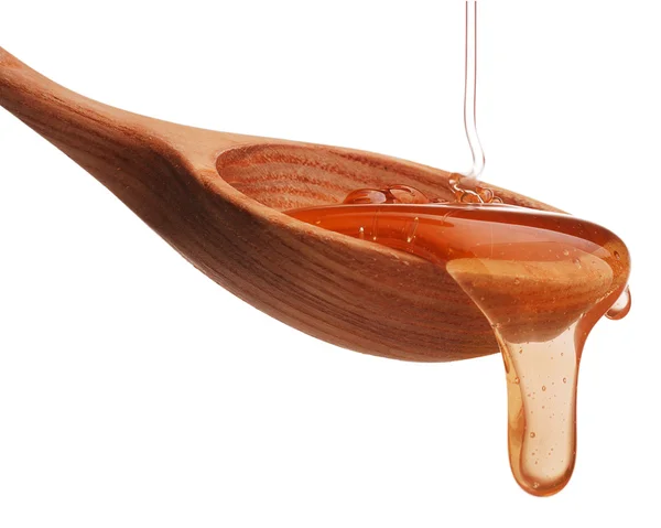 Honey dripping from a wooden spoon — Stock Photo, Image