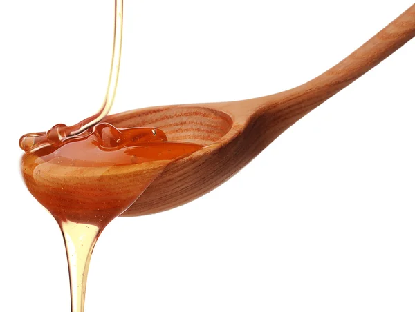 Honey dripping from a wooden honey dipper — Stock Photo, Image