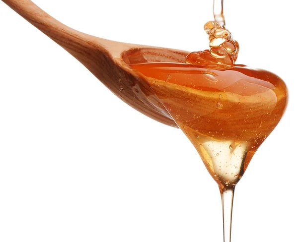 Honey dripping from wooden dipper — Stock Photo, Image